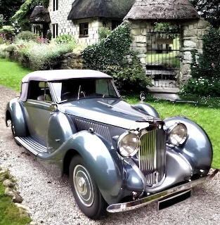 Silver-blue 1939 Lagonda V12 vintage car in front of thatched cottage