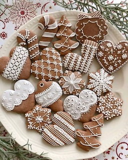 Plate of decorated gingerbread cookies with white icing in holiday shapes on a Christmas tablecloth