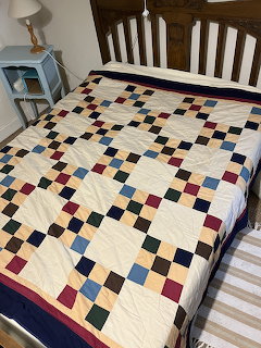 Colorful ninepatch patchwork quilt with geometric squares on white bed