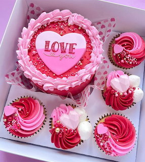 Pink Valentine cake with LOVE heart decoration and red velvet cupcakes with swirled frosting and heart toppers