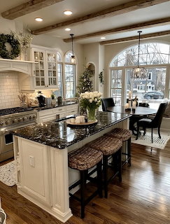 White kitchen with granite island, wicker stools, and arched windows showing snowy winter landscape