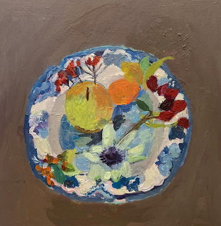 Overhead view of painted decorative plate with fruit and flowers on brown surface