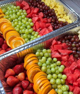 Two trays of assorted fresh fruit including oranges, strawberries, grapes, watermelon, and pineapple