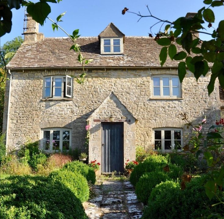 Stone cottage exterior with blue front door and garden path surrounded by shrubs