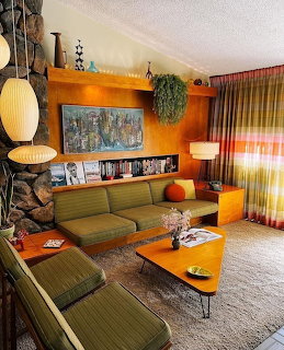 Mid-century modern living room with green sofa, wood paneling, stone fireplace, and retro decor