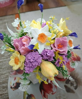 Colorful spring bouquet with tulips, daffodils, and purple flowers on table