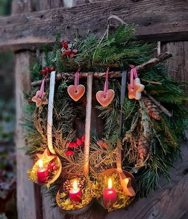 Rustic Christmas wreath with candles and heart ornaments on a wooden fence