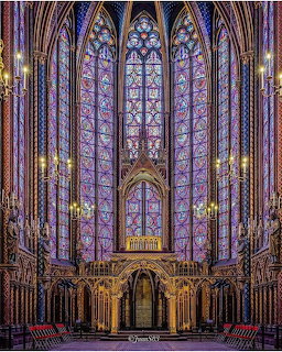 Ornate Gothic chapel interior with tall stained glass windows, vaulted arches, and golden altar illuminated in purple and blue