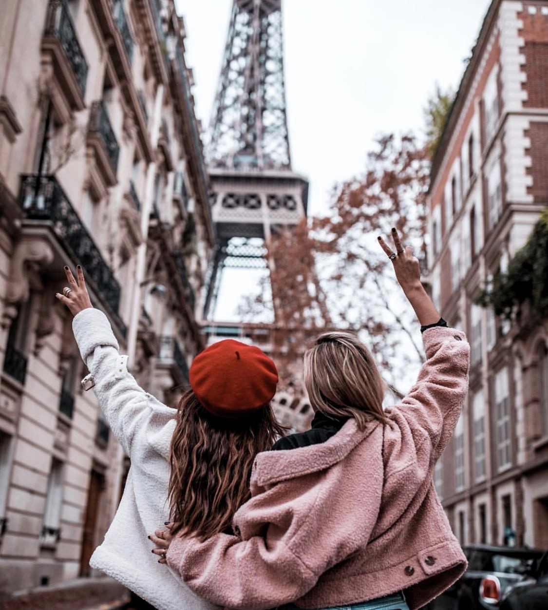 Two women hugging on a Paris street with the Eiffel Tower in the background