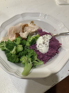 White plate with turkey slices, mashed purple sweet potato with sour cream, and broccoli