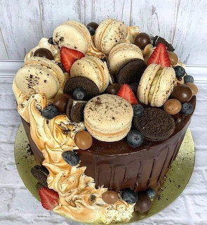 Chocolate cake decorated with macarons, berries, and chocolate candies