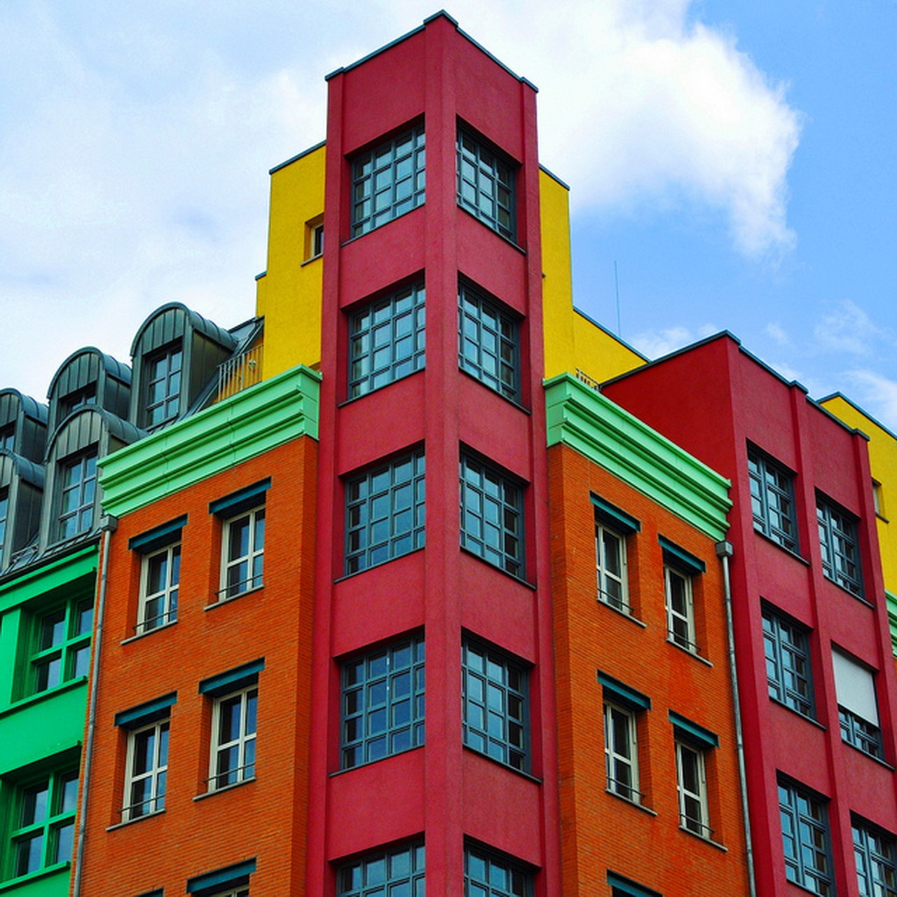 Colorful modern apartment building with red, yellow, orange and green facade blocks and geometric windows