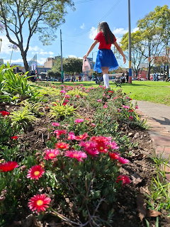 Woman standing in colorful flower garden on sunny day in park