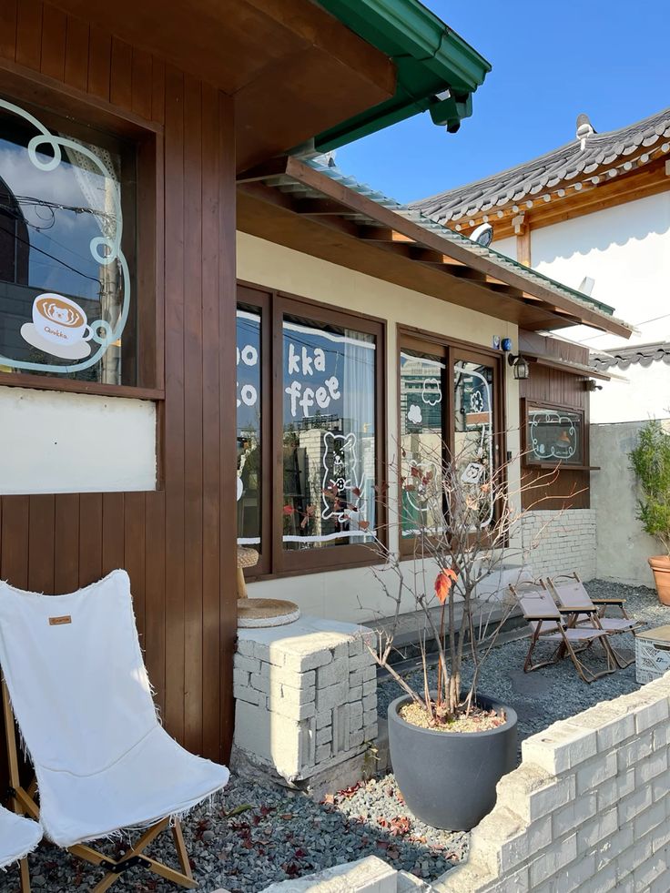 Wooden coffee shop exterior with white chair, potted plant, and outdoor seating area