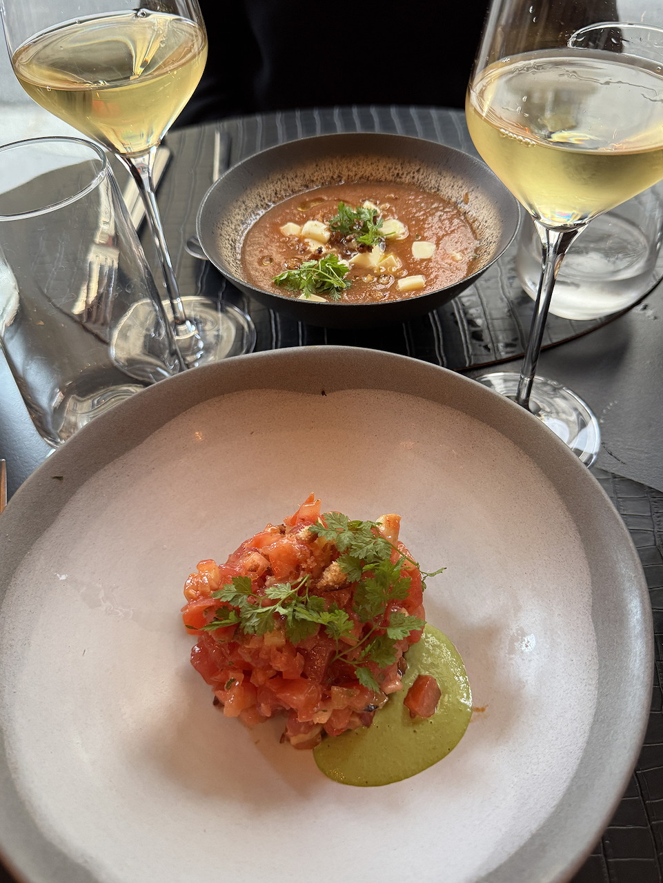 Restaurant table with two white plates of food and two glasses of white wine