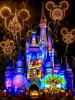 Cinderella Castle lit with blue and purple lights, Mickey Mouse firework shapes in gold above