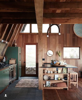 Modern kitchen interior with wood walls, open shelving, skylight, and pendant lighting