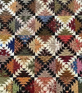 Patchwork quilt with colorful geometric star patterns in repeating blocks