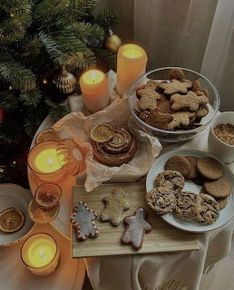 Christmas cookies arranged on white plates with lit candles and evergreen branches