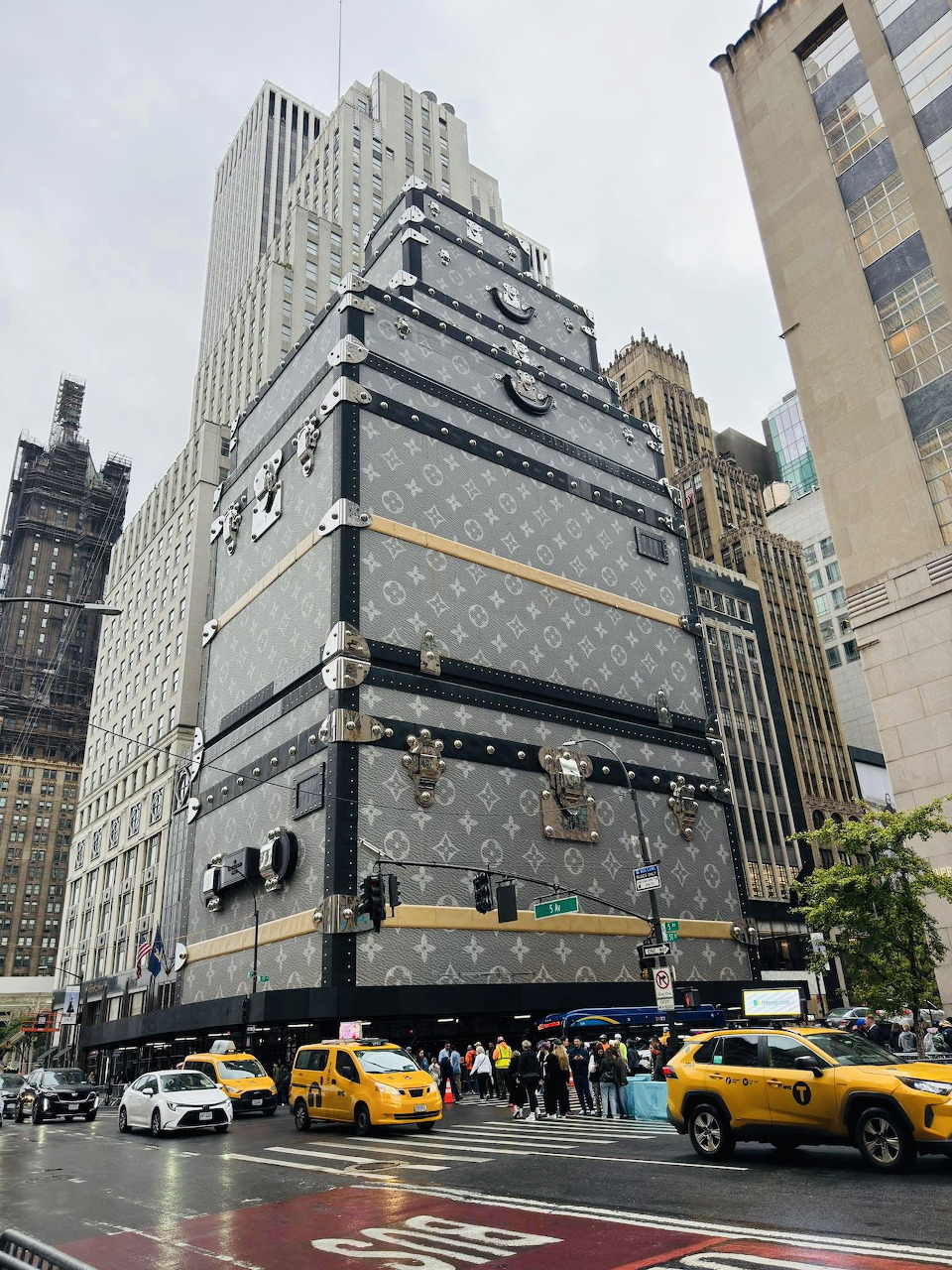Manhattan street with tall buildings, yellow taxis, and pedestrians crossing at intersection