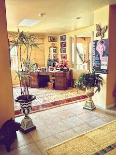 Bright residential foyer with yellow walls, plants, ornate table, tile floor, and decorative accents