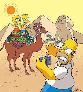 Homer Simpson with Lisa and Bart riding camels in desert with mountains
