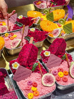 Colorful desserts with dragon fruit, citrus slices, and edible flowers arranged on decorative plates