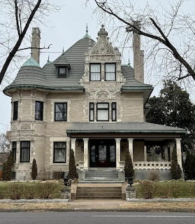 Large Victorian house with ornate trim, turret, and front porch viewed from the street
