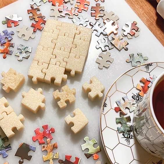 Jigsaw puzzle pieces spread on table with wooden organizers and tea cup