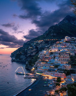 Positano Italy coastal town illuminated at twilight with buildings on steep cliffs above the Mediterranean Sea