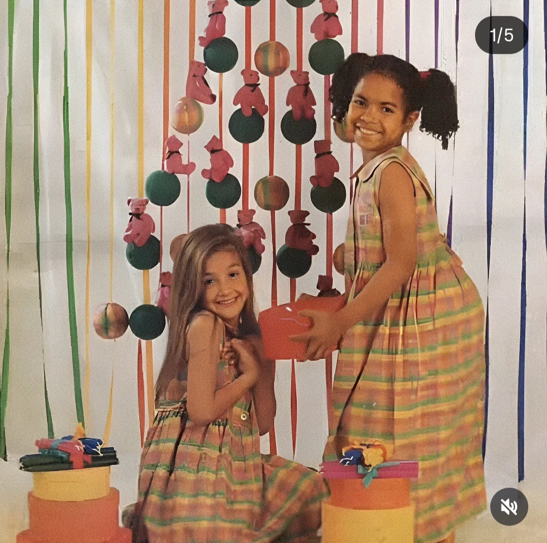 Two young girls in matching dresses with gift boxes and hanging decorations