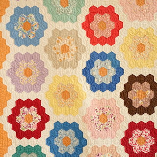 Colorful flower garden quilt with hexagon patchwork blocks on a cream background