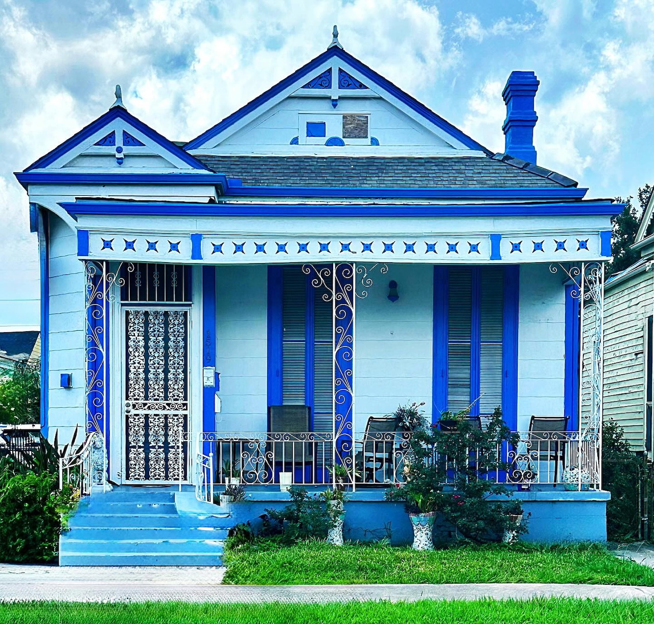 Bright blue Victorian cottage with white decorative trim and front porch