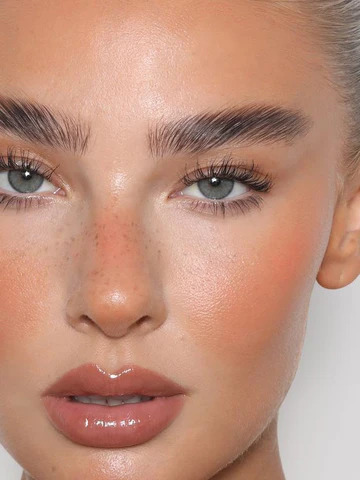 Close-up portrait of a woman with natural makeup, glossy lips, and glowing skin