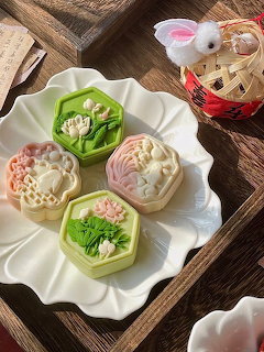 Pastel floral mooncakes on a white plate set on a wooden tray