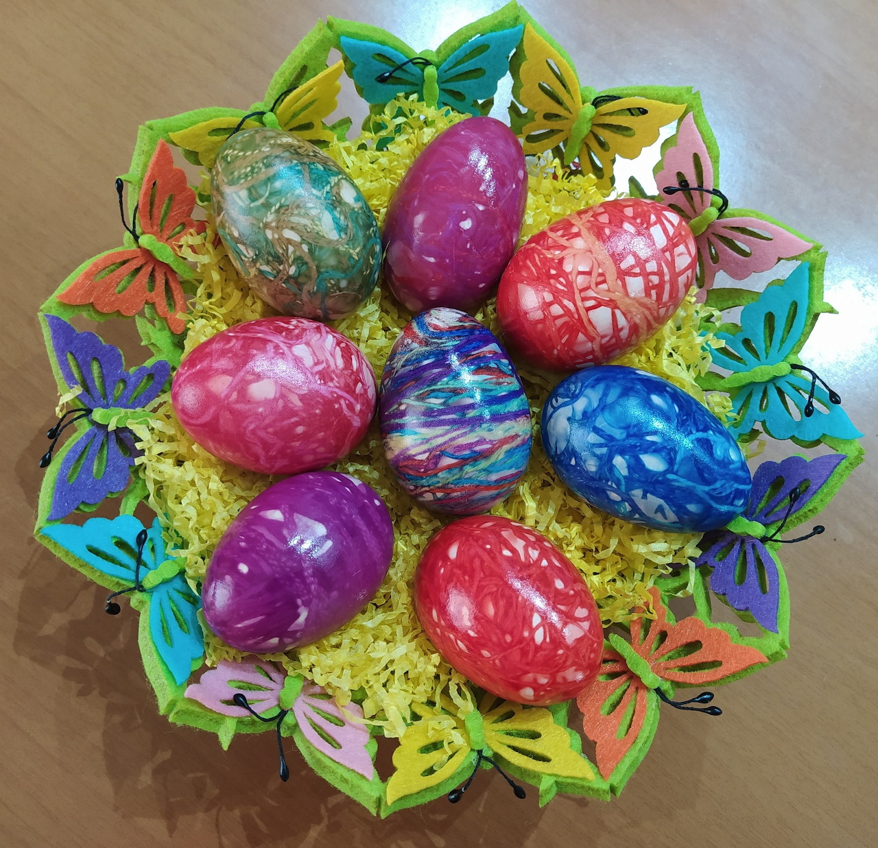 Colorful decorated Easter eggs on a festive paper doily with yellow decorative grass