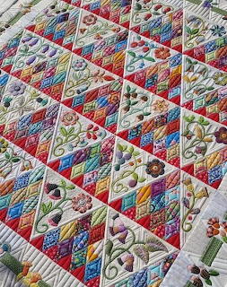Colorful patchwork quilt with triangular blocks, floral embroidery, and geometric patterns in various colors