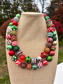 Christmas necklace with red, green, and white patterned beads on display bust