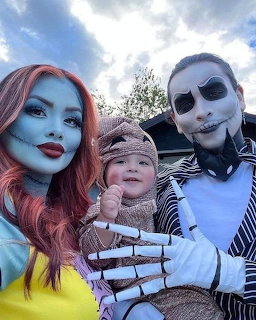 Three people in Halloween makeup and costumes posing together outdoors under cloudy sky
