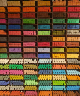 Colorful art pastels arranged in organized rainbow rows on display shelves