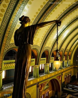 Bronze statue with lamp inside an ornate arched station interior