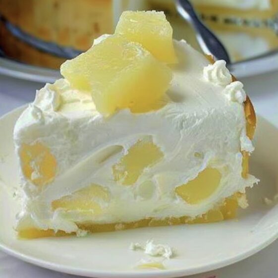 Slice of white cream cake with pineapple chunks and whipped cream topping on a plate