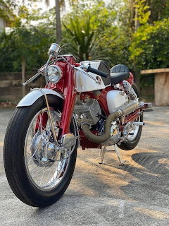 Red and white vintage Honda CB92 cafe racer motorcycle parked outdoors