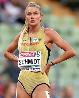 Female track athlete in a yellow Germany uniform standing on a sports field