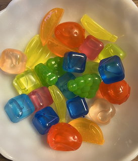 White bowl filled with colorful translucent reusable jelly ice cubes in various shapes and colors
