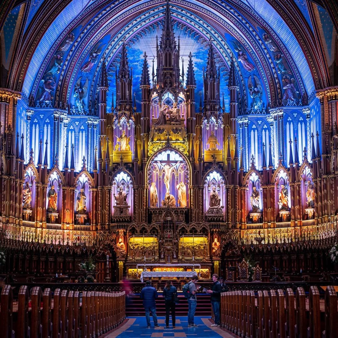 Gothic basilica interior with blue lit arches, golden altar, ornate wooden reredos and vaulted ceiling