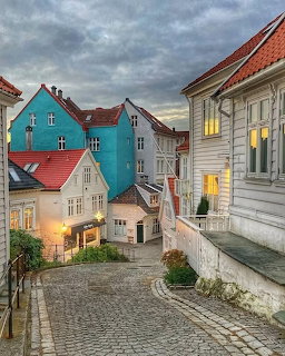 Cobblestone street lined with colorful wooden houses in Bergen, Norway at dusk