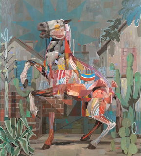 Colorful painted horse sculpture with abstract patterns in desert scene with cacti and buildings