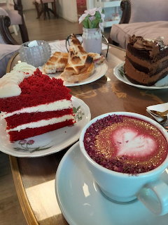 Cafe table with red velvet cake, chocolate cake, waffles, and a pink latte with heart latte art