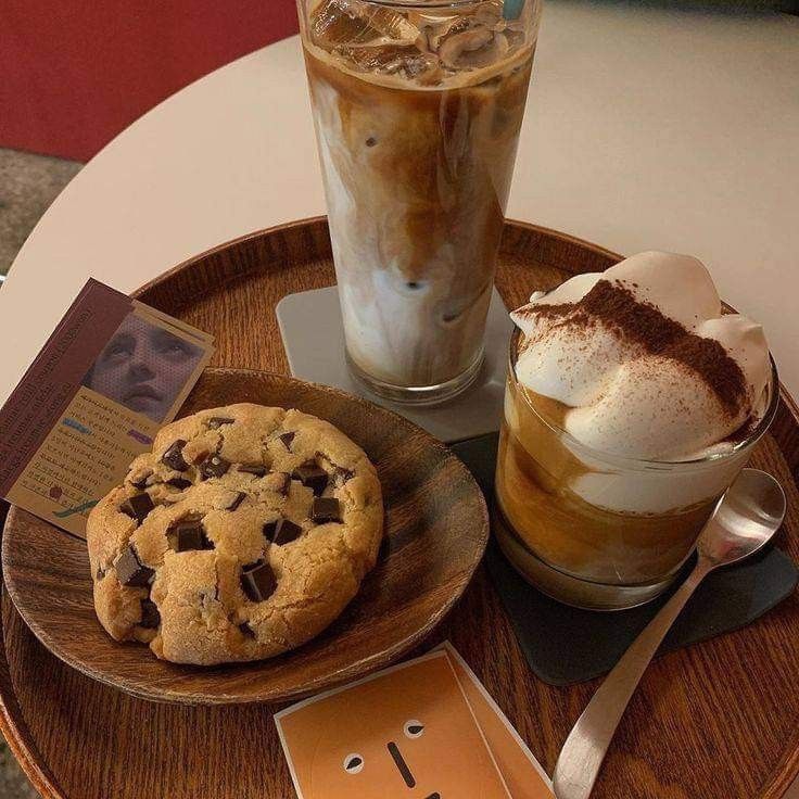 Iced coffee, Vienna Einspänner with cream, and chocolate chip cookie on wooden tray